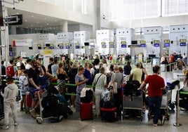 Passengers queue to check in their luggage.